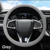 A close-up view of a grey steering wheel inside a car, showing the leather rim and controls.