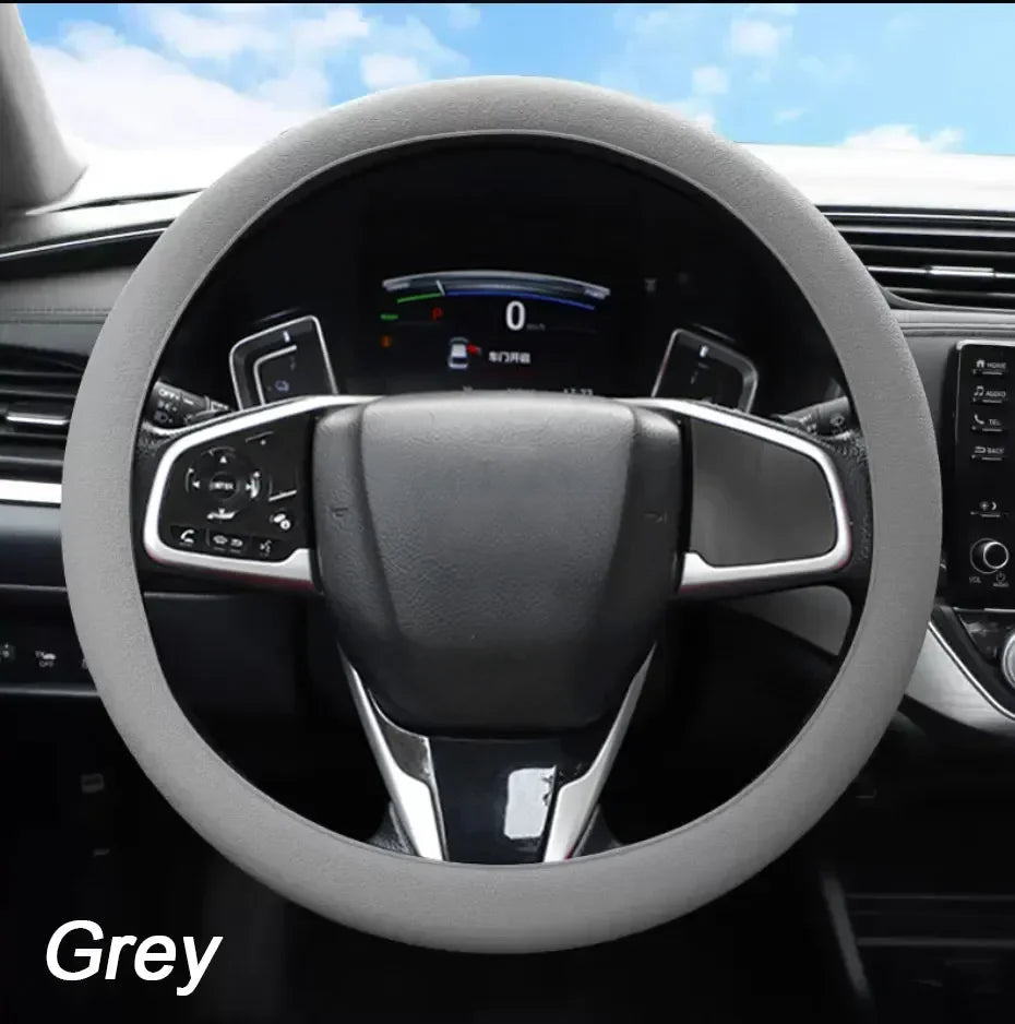 A close-up view of a grey steering wheel inside a car, showing the leather rim and controls.