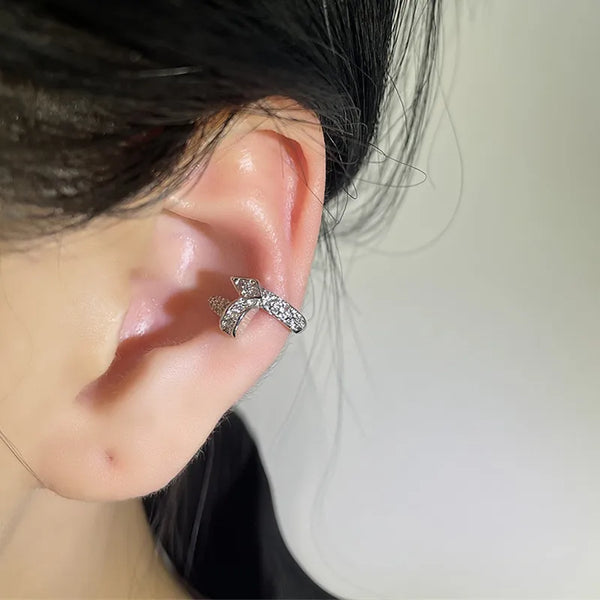 Aretes tipo argolla geométricos de circonita de plata puestos en la oreja de una persona.