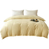 A beige washed cotton brushed duvet cover with white pillows and a dark tray containing a candle on a bed.