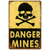 A vintage metal tin sign with a skull and crossbones symbol and the text DANGER MINES on a yellow background.