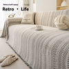 Nahaufnahme eines beige-schwarzen Chevron-Muster-Sofaüberwurfs mit einem cremefarbenen Kissen und einer weißen Tasse auf dem 