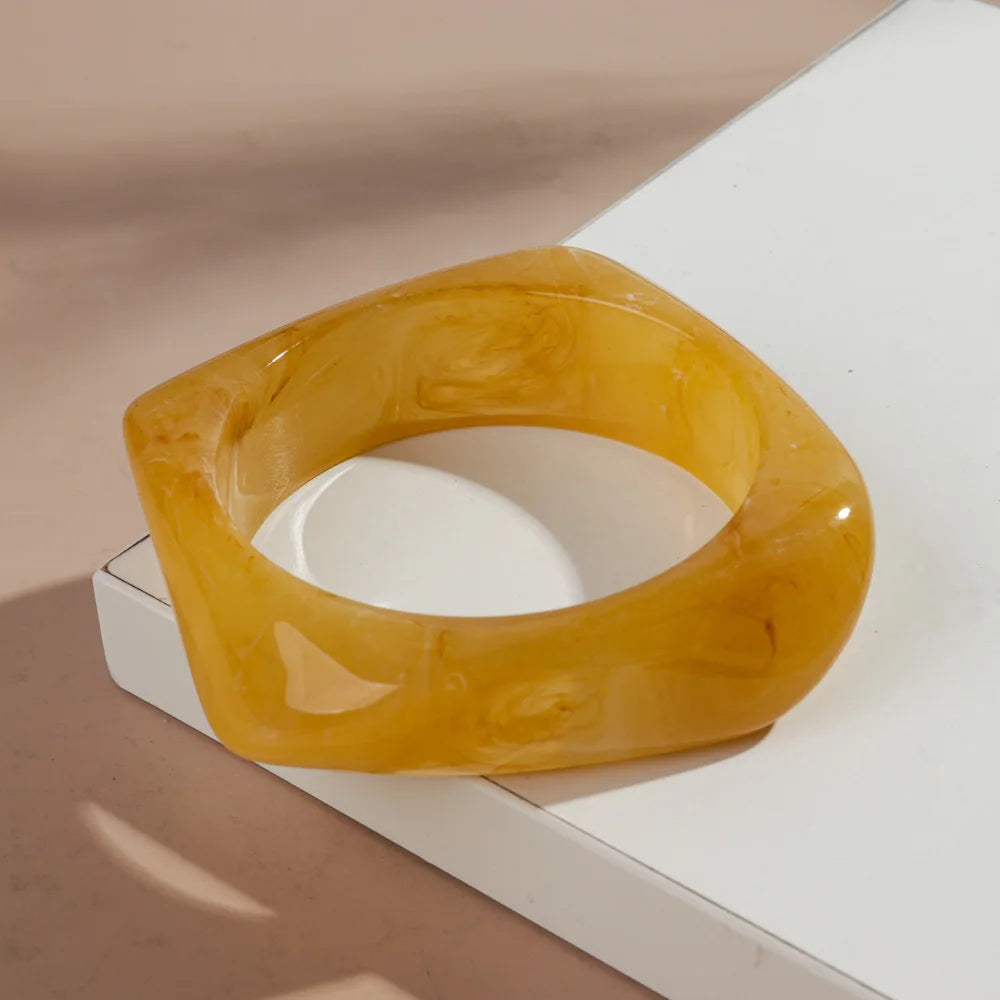 Bracelet manchette acrylique géométrique vintage, couleur jaune ambre translucide, sur fond blanc.