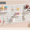 A white wall-mount pegboard organizer featuring shelves and hooks for storing various small items like dolls, tools, and acce