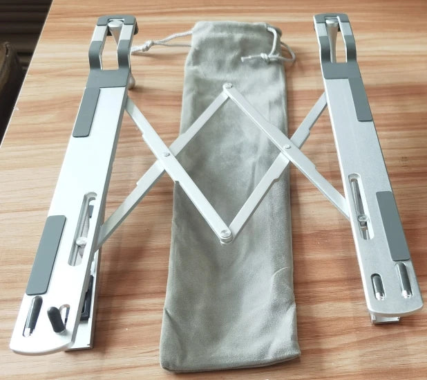 Foldable aluminum laptop stand with adjustable arms shown on a wooden surface.