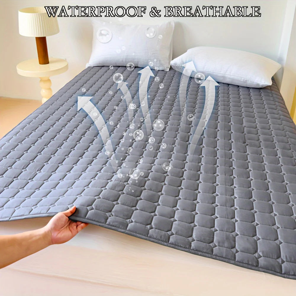 Grauer gesteppter wasserdichter Matratzenschutz auf einem Bett, der seine atmungsaktiven Eigenschaften zeigt.