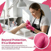 A woman wearing black apron is using pink disposable gloves to work on a kitchen surface.