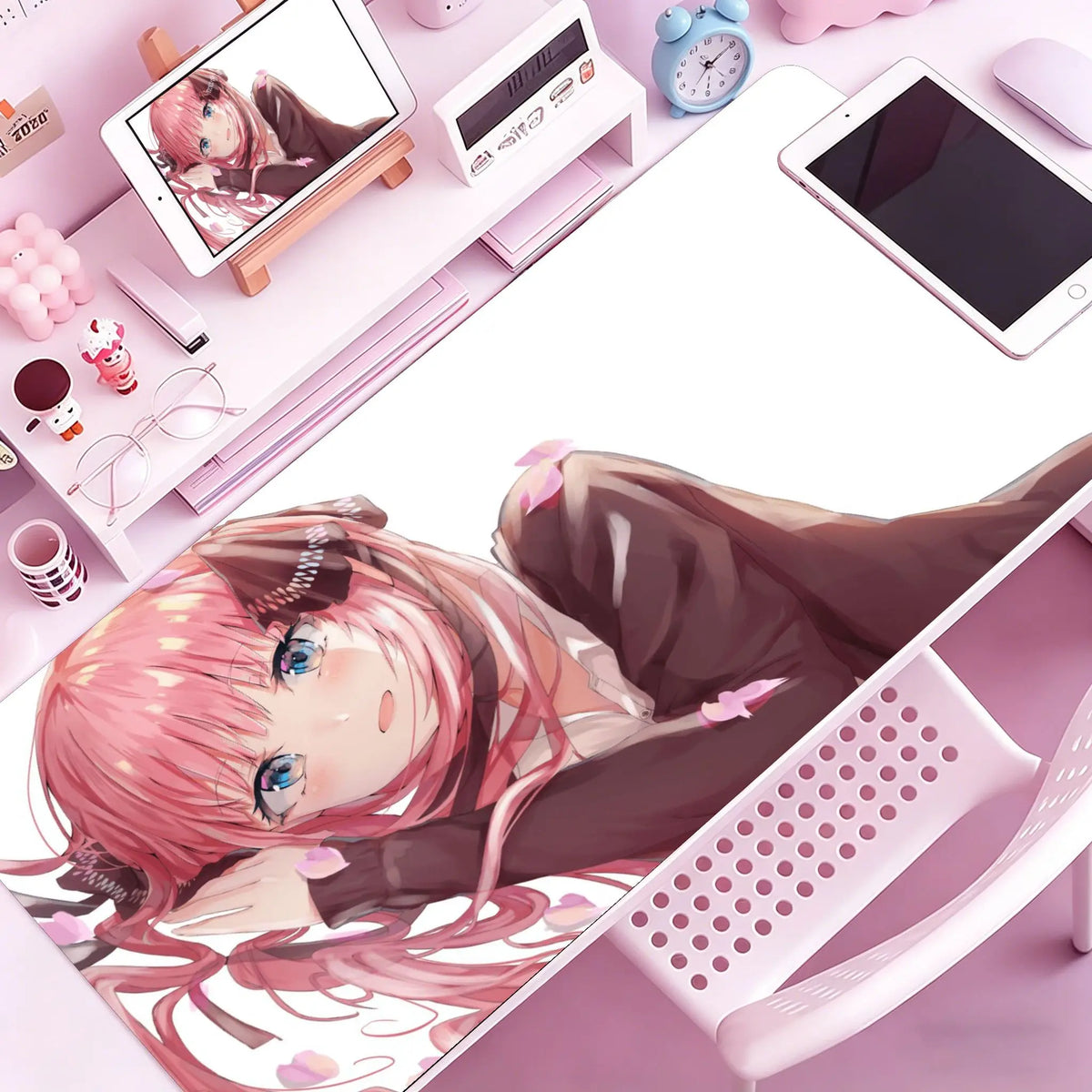 A close-up of a pink-haired anime character lying on a mouse pad with a non-slip rubber base on a desk.
