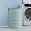 A cylindrical striped laundry basket with handles sits in front of a white LG washing machine.