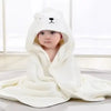 A baby wearing a white hooded towel with a cartoon bear design.