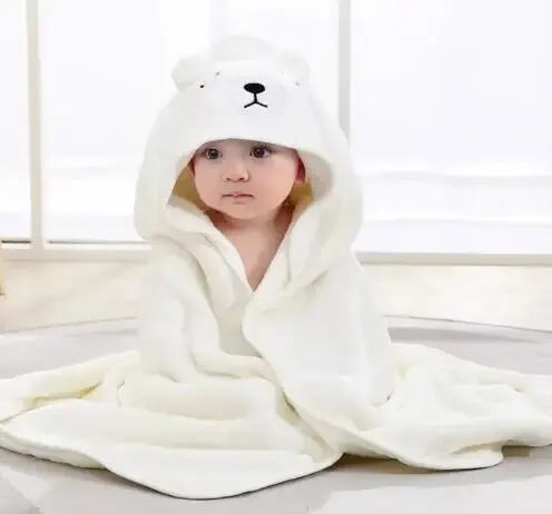 A baby wearing a white hooded towel with a cartoon bear design.
