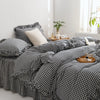 A black and white plaid duvet cover set with pillows on a bed next to a window.