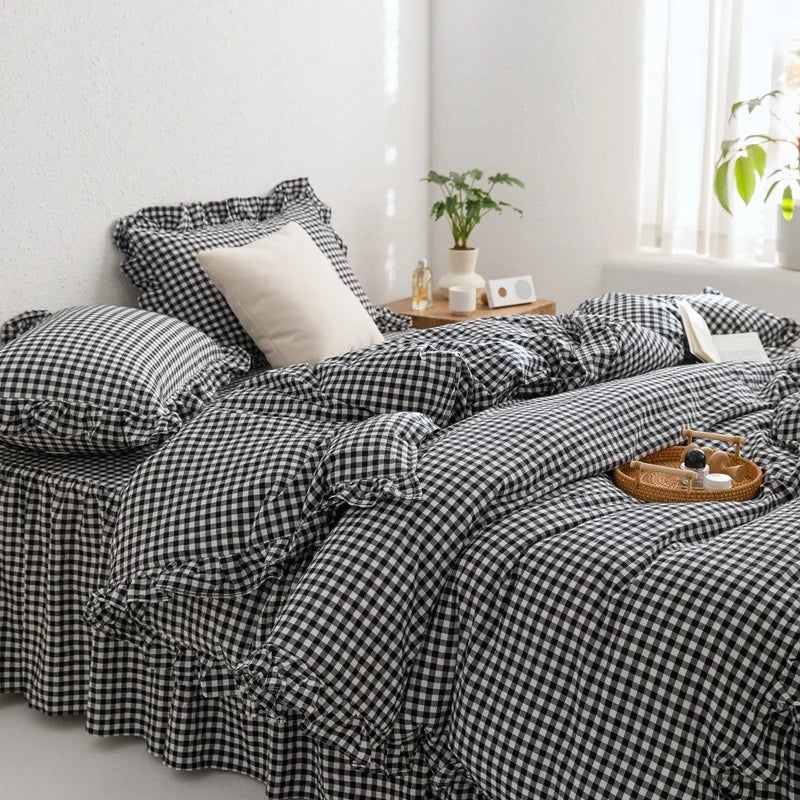 A black and white plaid duvet cover set with pillows on a bed next to a window.
