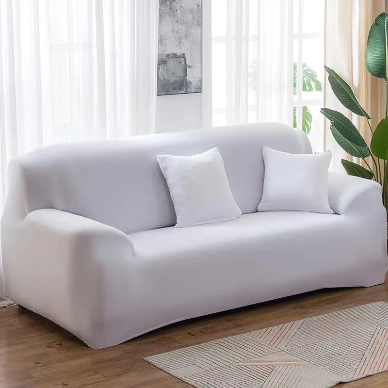 A modern, light gray elastic stretch sofa cover for a 3-seater sofa placed in a bright living room.