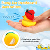A hand holds a yellow rubber duck ornament with a red felt hat and a gold ring, demonstrating the product for car dashboard d