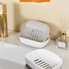 A white double-layered draining soap dish with a non-slip base is shown on a light surface.