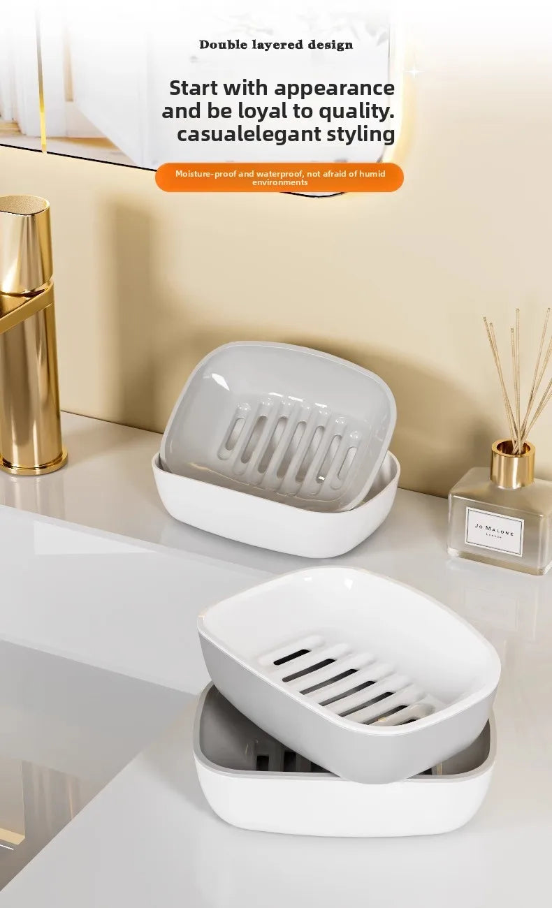 A white double-layered draining soap dish with a non-slip base is shown on a light surface.
