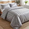 A gray satin striped jacquard duvet cover set displayed on a bed with natural wood and a woven rug.