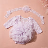 A light purple lace romper dress with a ruffled tutu skirt and matching headband laid on a pink background.