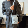 A person wearing a gray long-sleeve shirt holds a light gray bow-decorated casual crossbody bag.