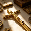 A close-up of a gold crucifix pen set featuring an INRI Jesus cross writing instrument on a light surface.