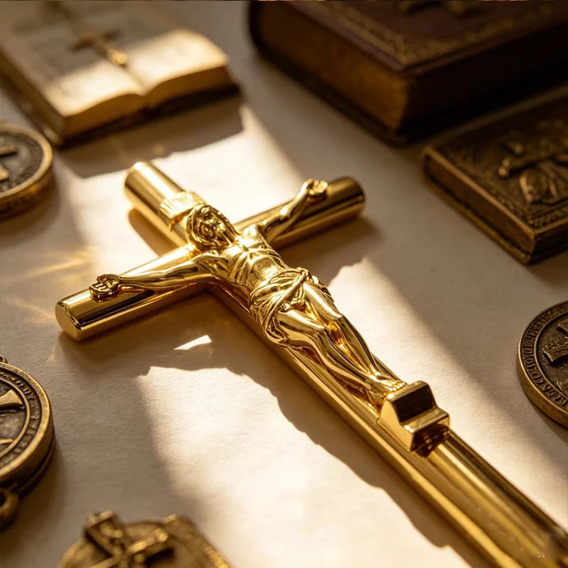A close-up of a gold crucifix pen set featuring an INRI Jesus cross writing instrument on a light surface.