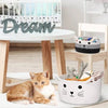 A small orange and white kitten is resting next to a white woven cotton rope storage basket with handles.
