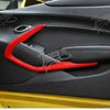 Close-up of a red interior trim piece installed in the black plastic panel of a yellow Chevrolet Camaro.