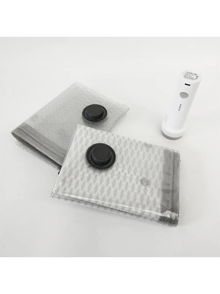 A clear reusable vacuum compression bag with a black seal and a white hand pump for travel and storage.