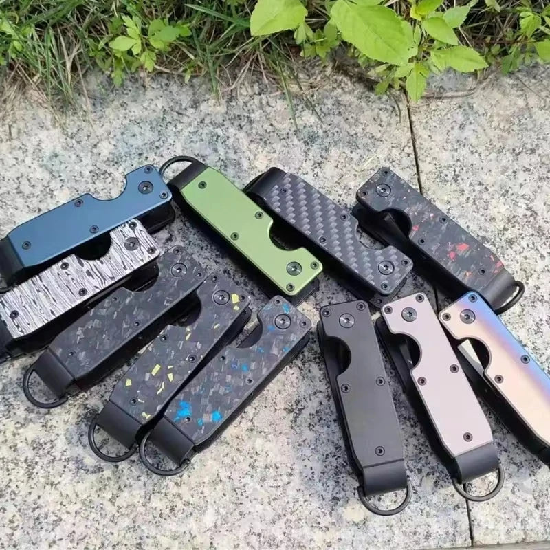 A collection of minimalist aluminum key organizers in various colors and finishes lying on a light-colored stone surface.