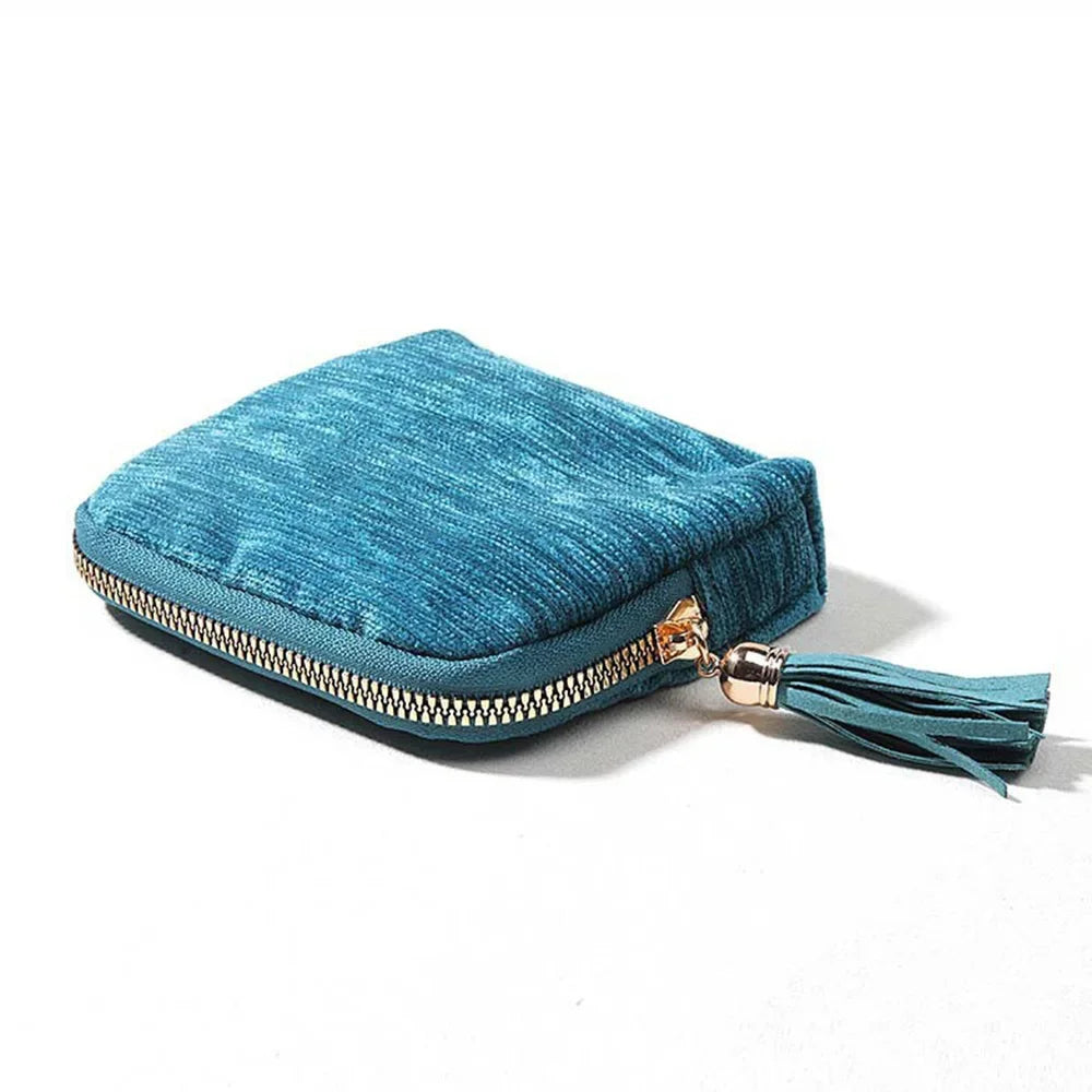 A teal velvet jewelry organizer bag with a gold-toned zipper and tassel detail.