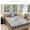 A luxury faux fur fitted sheet and pillowcase set displayed on a bed with sheer curtains.