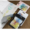 A collection of colorful decorative bookmarks and paper clips are displayed on a brown fabric background.