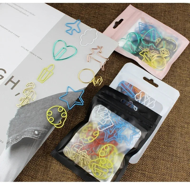 A collection of colorful decorative bookmarks and paper clips are displayed on a brown fabric background.
