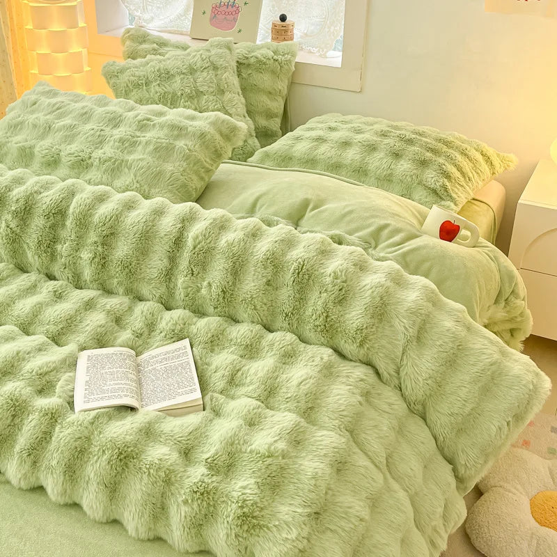 A set of four ultra-soft, fluffy, light green faux fur pillows and blankets arranged on a bed.