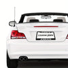A white car with a humorous aluminum license plate frame that says Scares Me Too