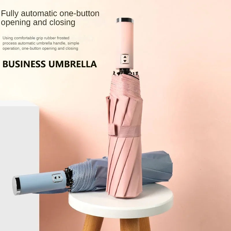 A pink business umbrella with a silver handle is shown standing on a white surface.