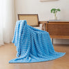 A bright blue soft and cozy brushed flannel throw blanket draped on a light wooden floor.