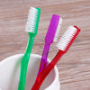 A set of six premium hard bristle toothbrushes in green, purple, and red are displayed in a white bowl.