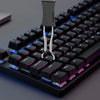 A close-up view of a black mechanical keyboard with a metal keycap puller and adjuster tool inserted into a keycap.