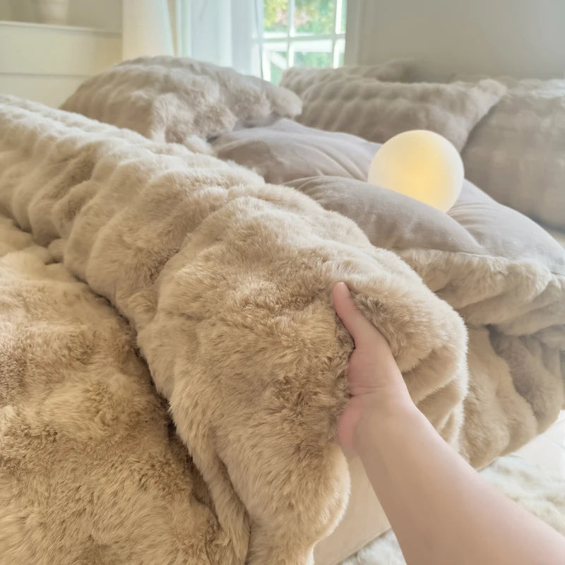 A hand is touching a fluffy beige fleece duvet cover with a rabbit design, resting on a bed.