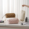 A beige quilted storage bag for a portable hair dryer is displayed on a white surface.
