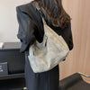 A woman holds a vintage matte leather crossbody hobo bag with an adjustable strap against a light wooden background.