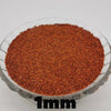 A close-up view of reddish-brown decorative stone pebbles, approximately 1mm in size, filling a clear glass bowl.