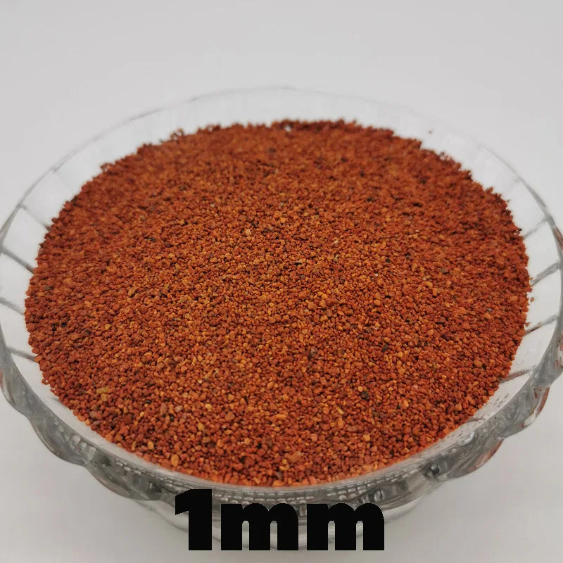 A close-up view of reddish-brown decorative stone pebbles, approximately 1mm in size, filling a clear glass bowl.