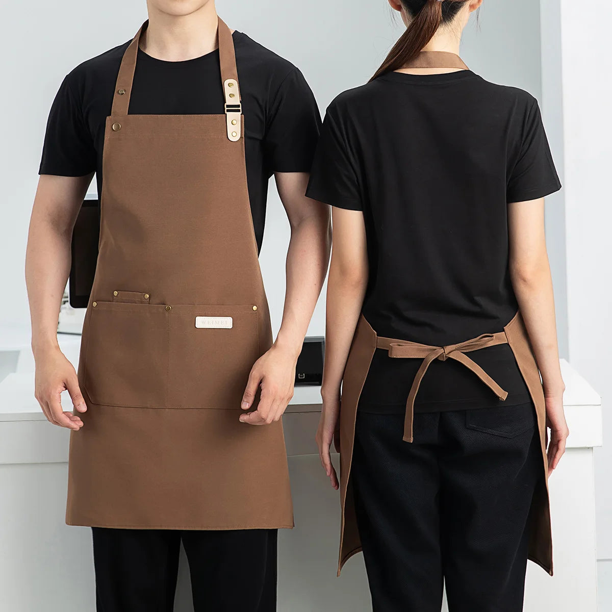 A person wearing a brown waterproof canvas chef apron over a black shirt and pants.