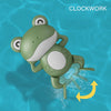 A green wind-up swimming frog toy is shown underwater with a yellow arrow indicating movement.