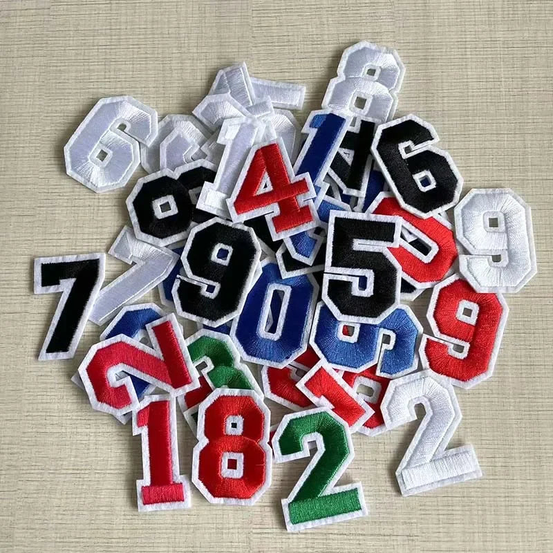 A collection of multicolor iron-on 3D number patches from 0 to 9 are scattered on a light background.