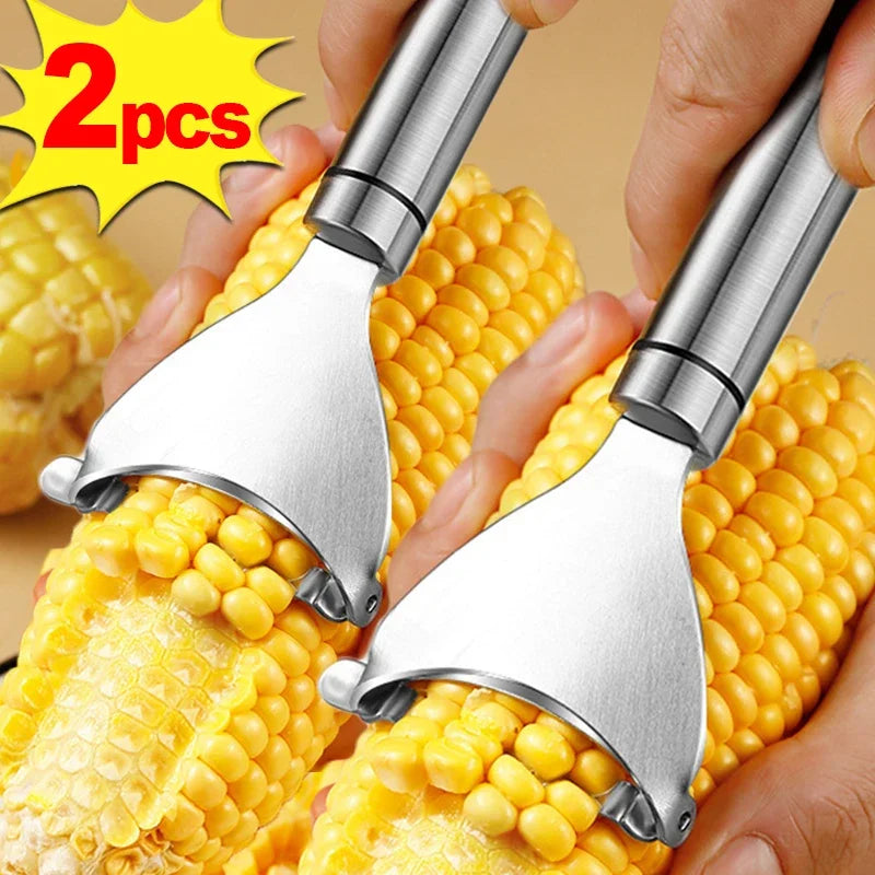 A hand is using a stainless steel corn peeler to peel corn kernels from the cob.