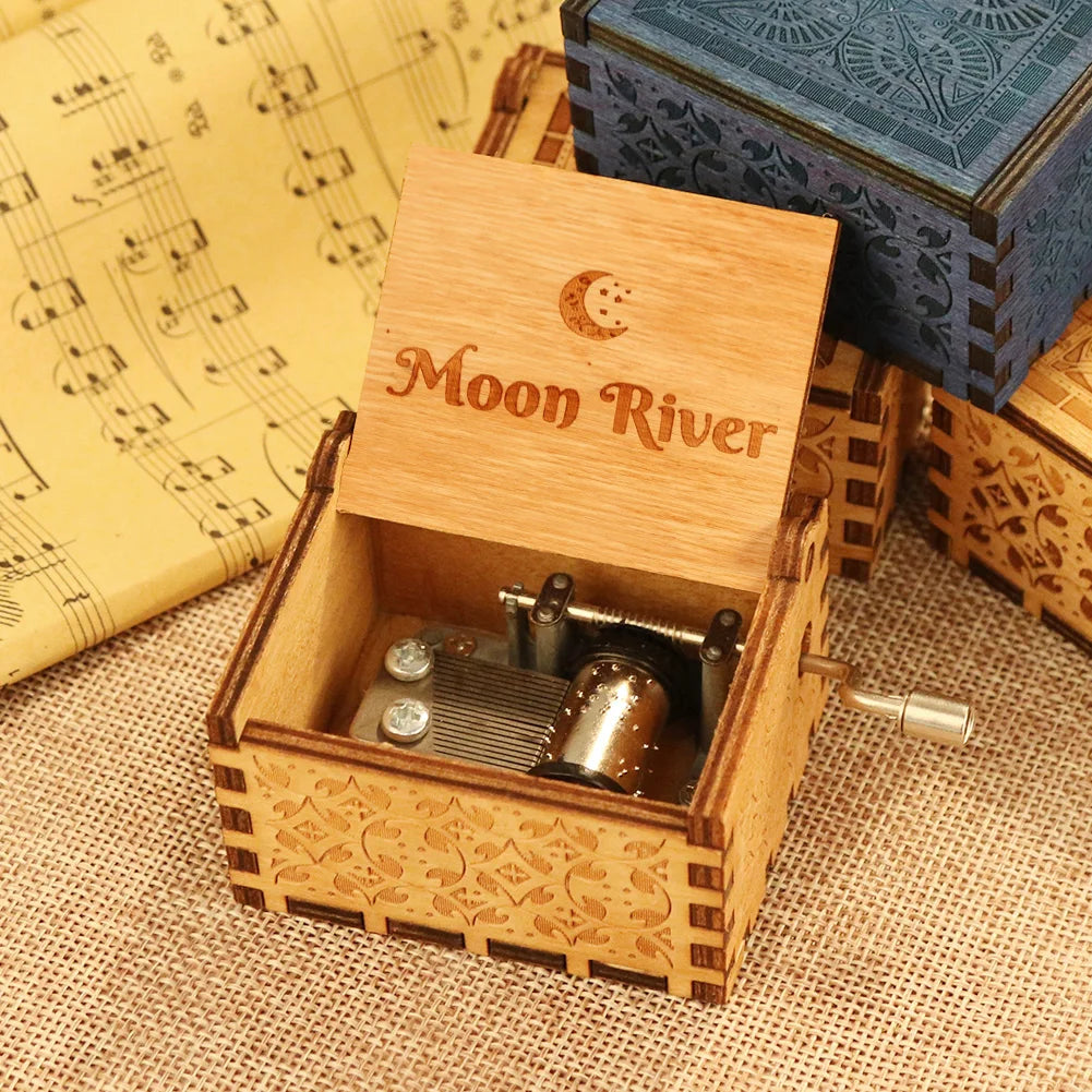 A hand-cranked wooden music box with a lid featuring a moon design and an inner mechanism.